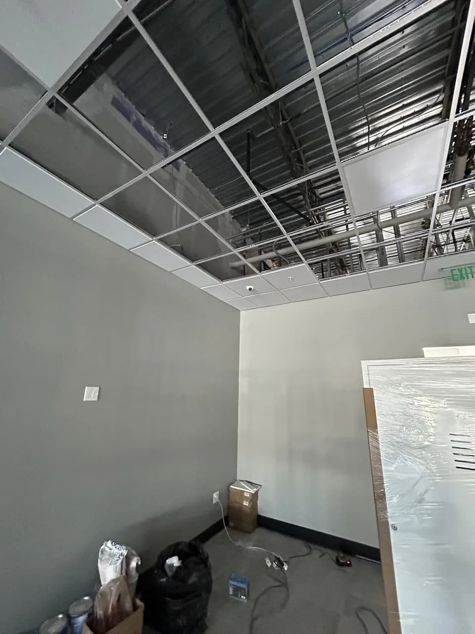 Finished back-room walls beneath an open ceiling grid in the Consumer Cellular Fort Myers tenant space
