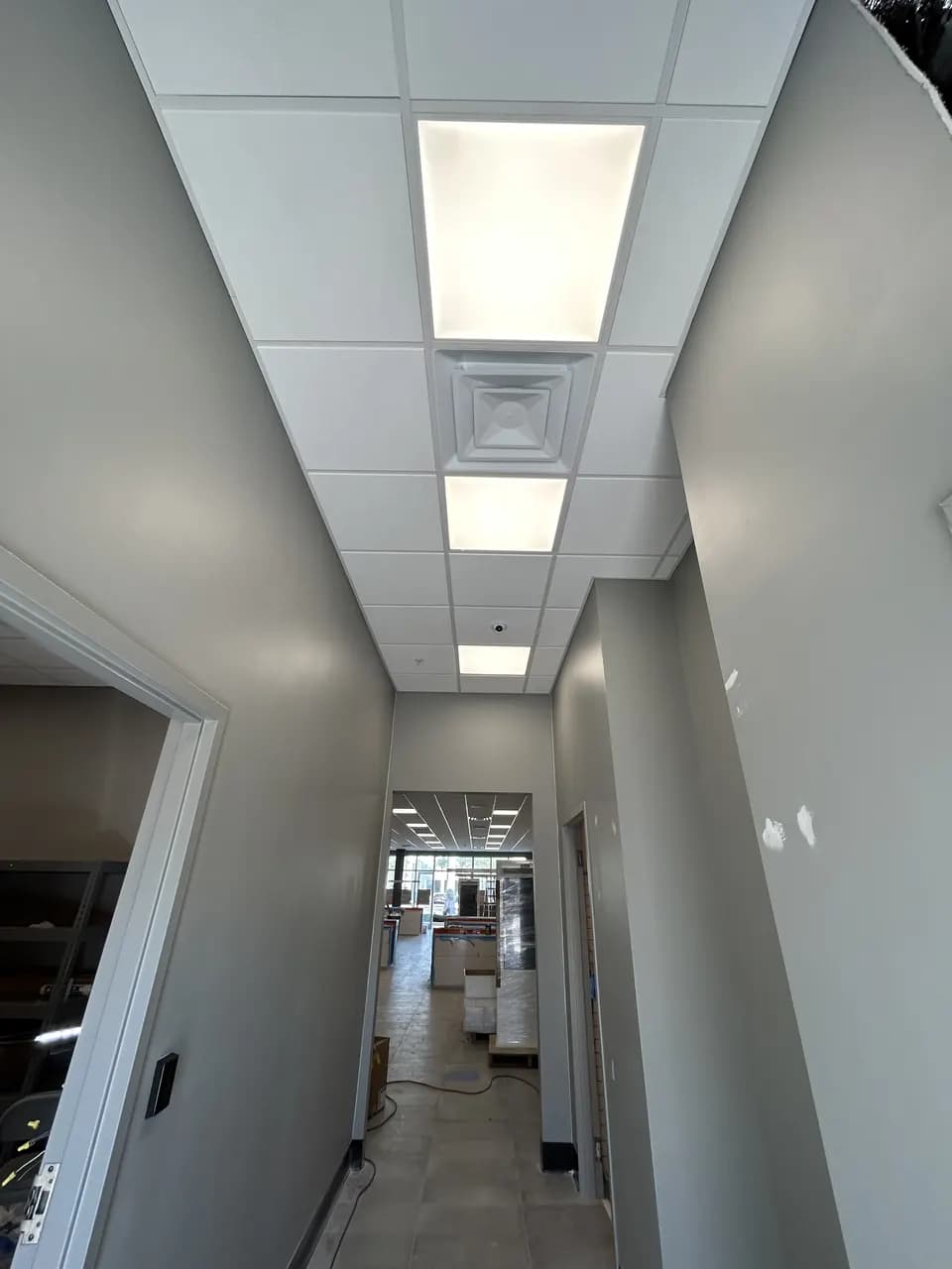 Back-of-house corridor with ceiling tiles and lighting installed during the Consumer Cellular Fort Myers tenant improvement
