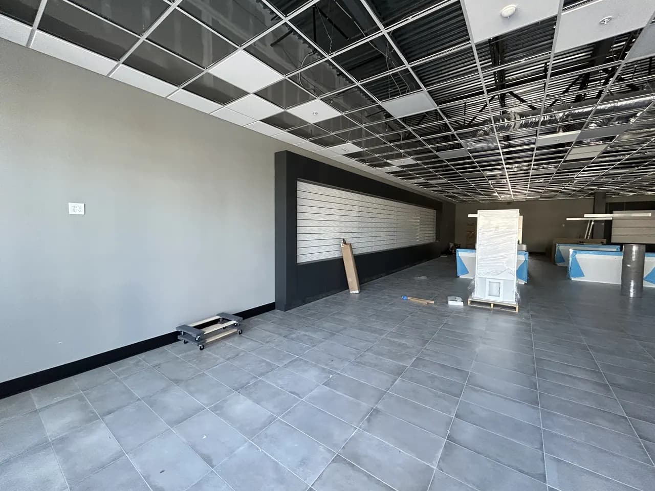Tile flooring and finished walls beneath the open ceiling grid during the Consumer Cellular Fort Myers build-out