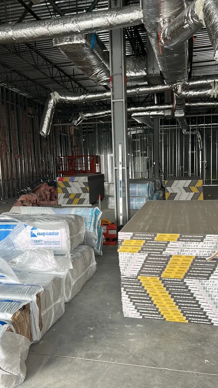 Wrapped construction materials staged beneath exposed ductwork in the Consumer Cellular Fort Myers tenant space
