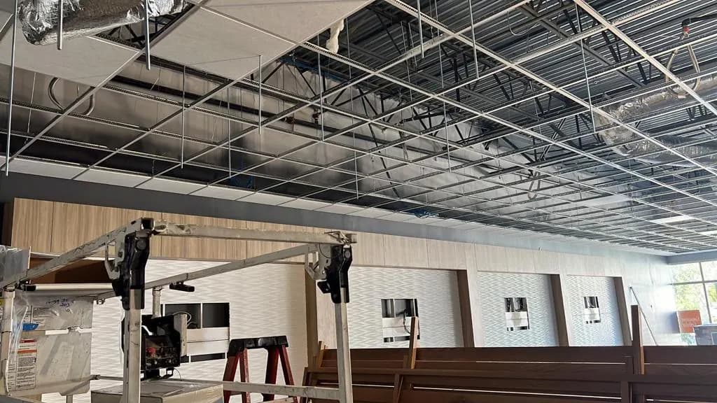 Wood-look retail feature wall and display recesses beneath the ceiling grid at Consumer Cellular Fort Myers