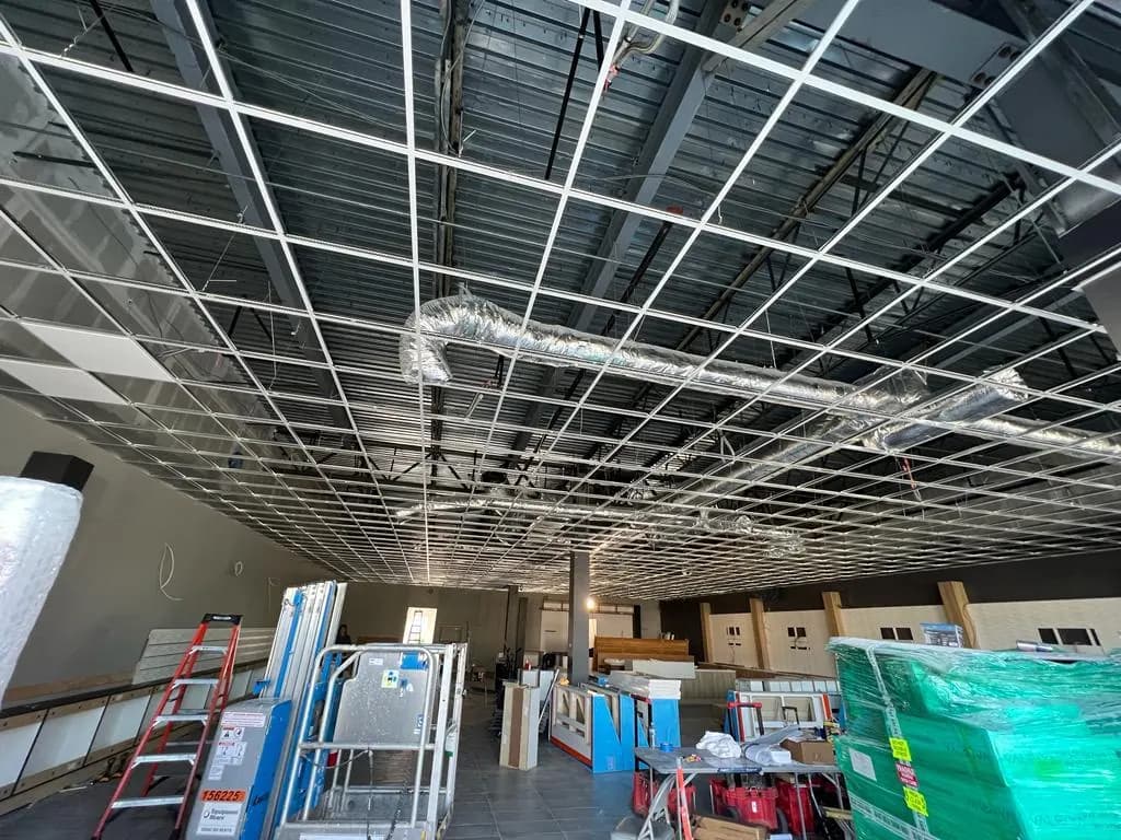 Suspended ceiling grid and insulated ductwork above materials and equipment in the Consumer Cellular Fort Myers sales area