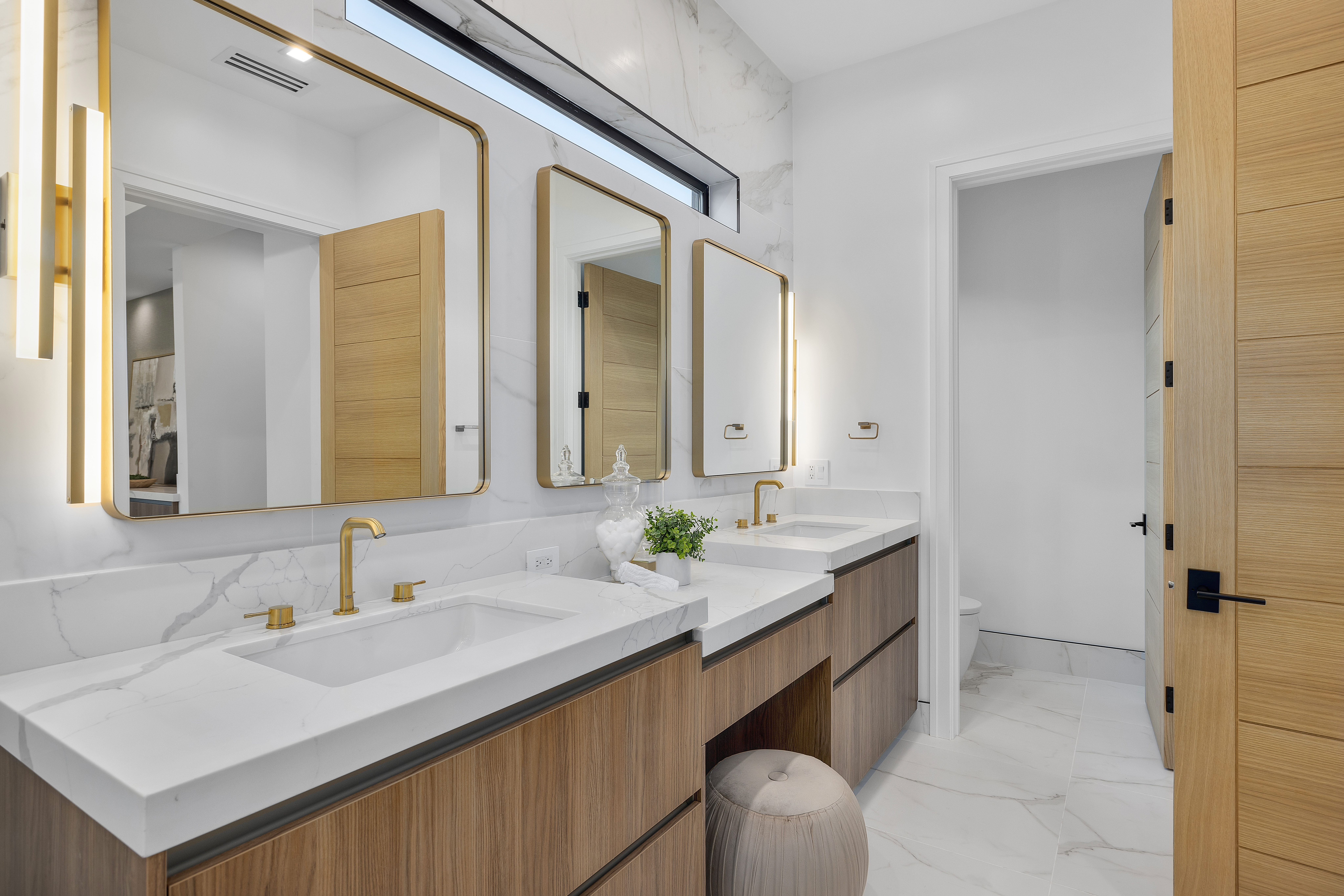 Primary bath with marble counters and brass fixtures — DWD Builders